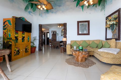 Casa del Secreto’s living room under a painted jungle ceiling with a toucan-painted armoire and carved columns