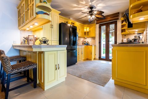 Casa del Secreto’s yellow country kitchen with carved cabinets and a breakfast bar