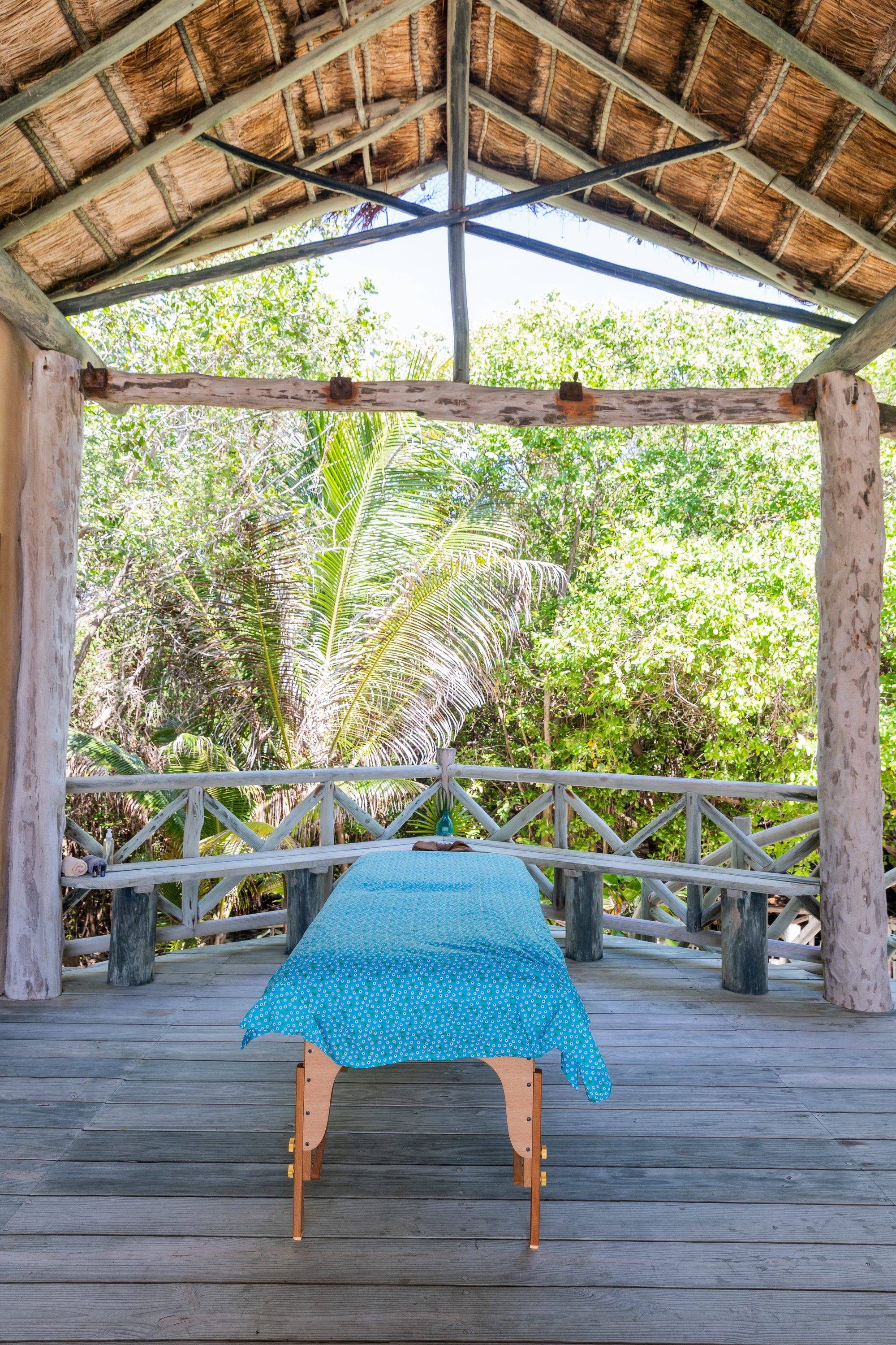 A massage table set under a palapa deck surrounded by the estate's greenery