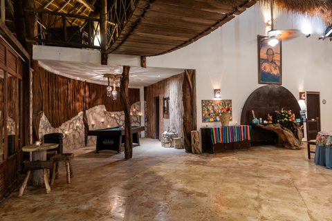 Inside the estate's grand palapa at night — pool table and candle-lit stone walls on the games level