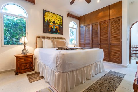A Villa Canteena bedroom with a calla-lily painting and wooden louvered wardrobe