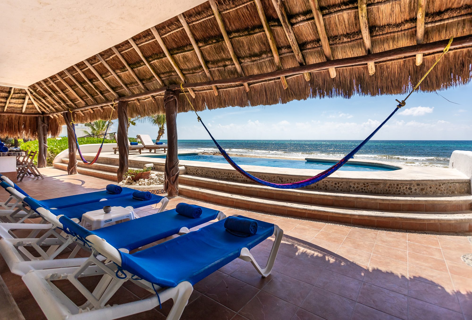 Villa Canteena's palapa-shaded pool terrace with hammocks and loungers opening onto the Caribbean