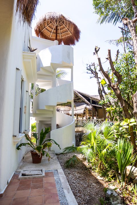 A white spiral staircase climbing Villa Canteena’s side to a thatched palapa lookout