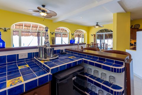 Villa Canteena’s blue-Talavera bar under yellow walls with hammocks and the sea beyond the windows