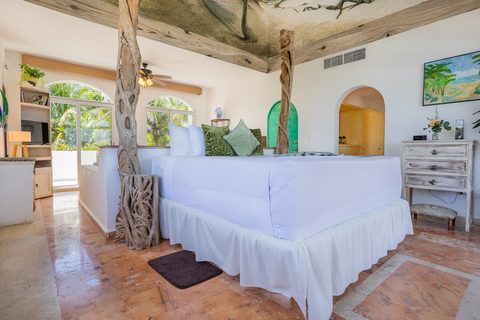 Villa Sarita’s master bedroom with driftwood posts under a painted sea-life ceiling mural