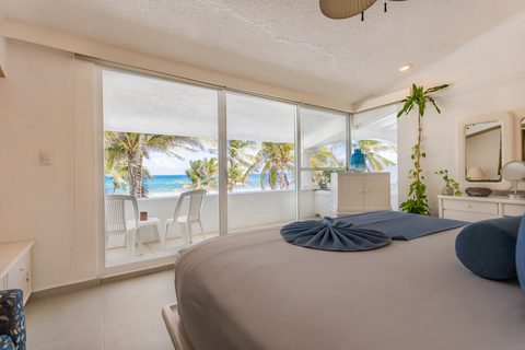 A bright Villa Tortuga bedroom opening to an ocean-view balcony