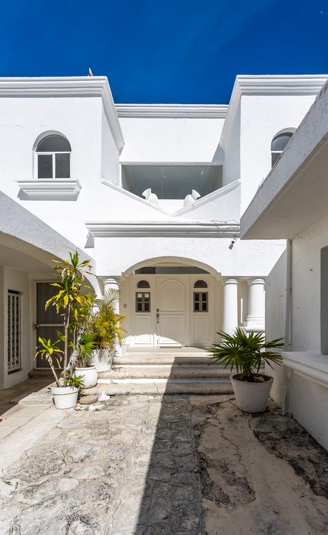 Villa Tortuga's whitewashed entrance courtyard with arched portico and potted palms