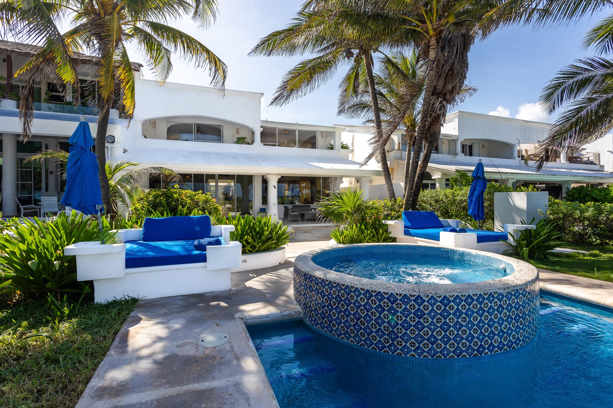 Villa Tortuga's Talavera-tiled hot tub and pool with blue daybeds beneath the villa's white facade