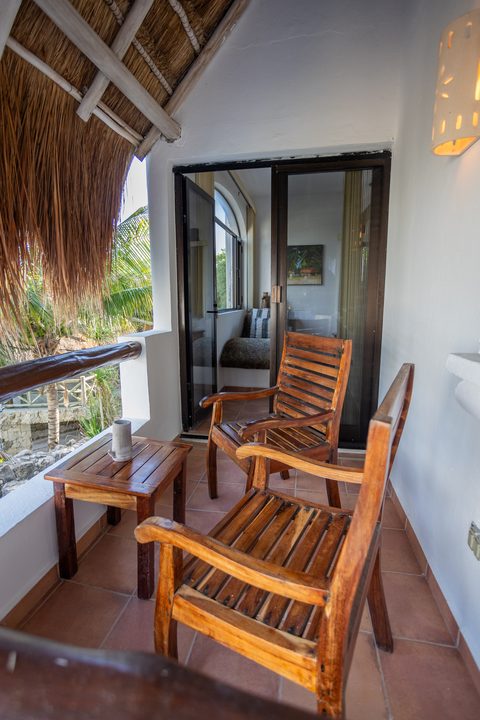 Wooden armchairs on Villa Umakiha’s thatch-shaded balcony over the gardens