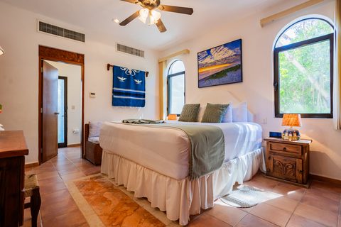 A Villa Umakiha bedroom with a woven Mexican wall hanging and windows into the greenery