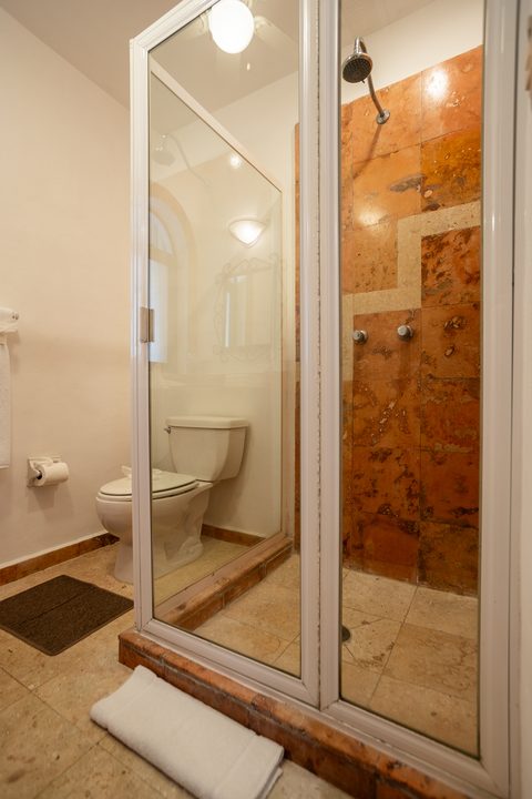 Villa Umakiha’s walk-in shower faced in rust-and-cream stone