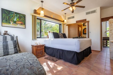 A beamed Villa Umakiha bedroom with a wide window into the palms