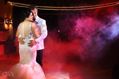 A newlywed couple's first dance under string lights in the estate's palapa