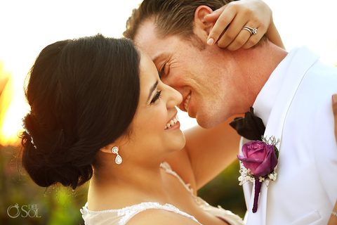 A close sunset portrait of the newlyweds, the groom's purple rose boutonniere in focus